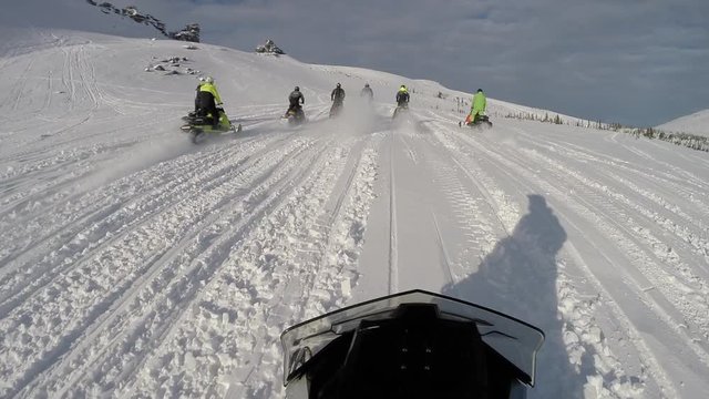 POV: Ryder is chasing a group of snowmobilers on a snow sports motorcycles. group riding on elite snowmobiles in a mountain valley. the concept of winter motorcycle tourism. First-person view