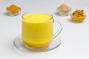 Golden latte on white background with ingredients for cooking. Indian drink turmeric golden milk .
