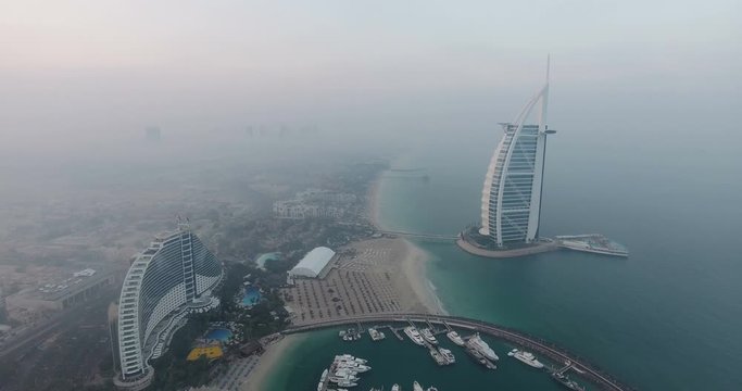 DUBAI, UAE - JANUARY 4, 2017: Aerial view of Burj al Arab hotel at sunrise. The Burj al-Arab is a symbol of Dubai and a luxury hotel standing on an artificial island next to Jumeirah beach. foggy day