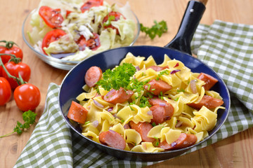 Österreichische Küche: Wurstfleckerln mit typischen Fleckerlnudeln, dazu ein kleiner Salat mit Steirischem Kernöl - Austrian cuisine: Pasta with fried sausages and a side salad with pumpkin seed oil