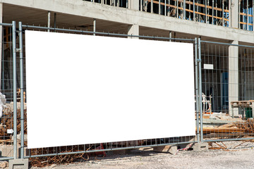 Blank white banner for advertisement mounted on the fence of construction site on a sunny day.