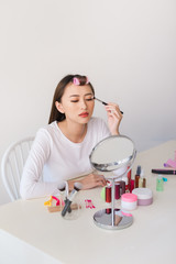 Attractive talented female blogger reviews beauty product for video blog, gives advice to girls and women, films process on camera.