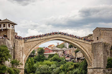 Een man springt van de oude brug &quot Stari Most&quot  terwijl het publiek op de brug hem toejuicht, Mostar, Bosnië en Herzegovina