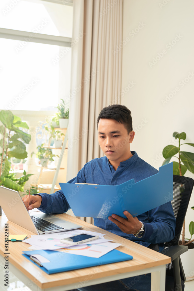 Poster man working on laptop with document paper at his working space.