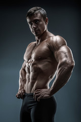 Fototapeta na wymiar Muscular and fit young bodybuilder fitness male model posing over black background. Studio shot on black background.