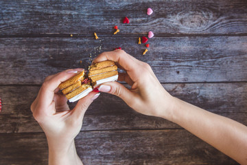 Baking Surprise Cookies with topping and icing on wooden background with pink heart. Woman holds a love letter