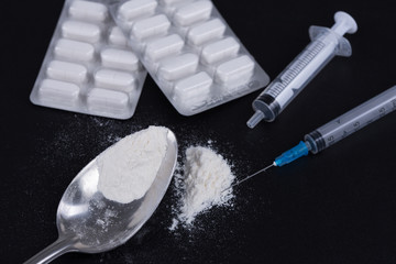 White pill, syringe and heroin on spoon. Drug addiction.