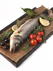 food photography of stuffed fish with lemon and herbs side view on a wooden kitchen board close up on a white background isolated