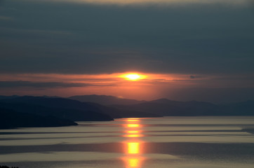 Fototapeta na wymiar Glare dawn over the distant hills with a vivid yellow track on the sea. Sunrise over the vast aquatics area of Black Sea, Crimea