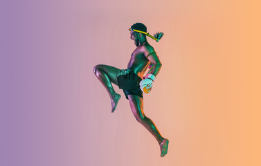 Muay thai. Young man exercising thai boxing on gradient background in neon light. Fighter...