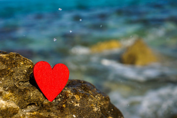 Fototapeta premium red heart on a stone in front of blue sea