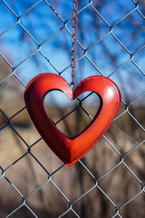 red heart hangs on a chain link fence
