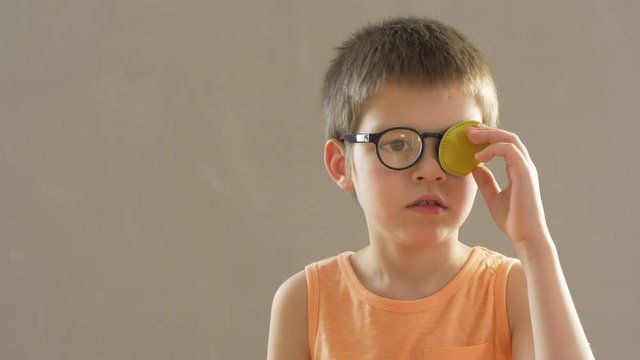 Portrait of funny child in new glasses with yellow spot to correct strabismus Orthopedic Boys Eye Patches nozzle for glasses for treatment of strabismus (lazy eye). Boy puts on and corrects glasses
