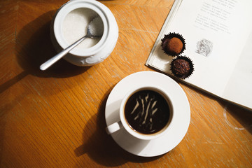 Black americano espresso coffee with chocolate sweets in cabinet for reading