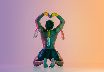 Muay thai. Young man exercising thai boxing on gradient background in neon light. Fighter...