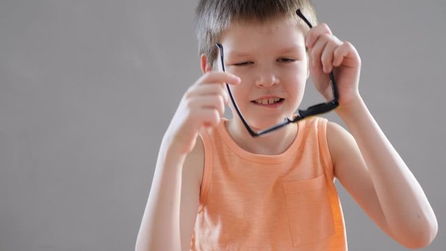 Portrait of funny child in new glasses with yellow spot to correct strabismus Orthopedic Boys Eye Patches nozzle for glasses for treatment of strabismus (lazy eye). Boy puts on and corrects glasses