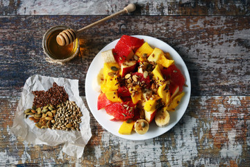 Fruit salad on a white plate. Healthy salad with fruits, honey and seeds. Healthy dessert. Proper...