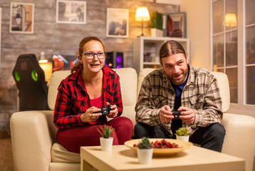 Gamers couple playing video games on the TV with wireless controllers in hands