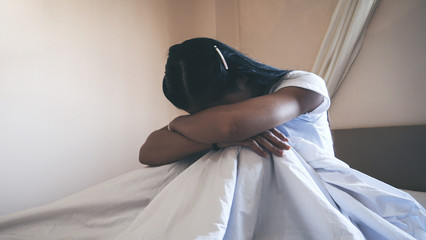 Asian girl sad in bedroom with dark light.