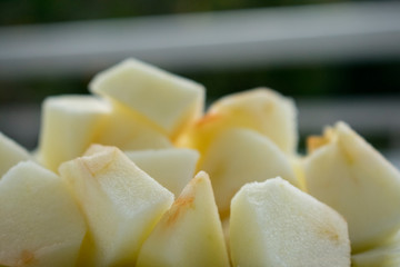 Primer plano de cubos de manzana pelados, en un plato y algo oxidados (marrones) después de cortarlos.