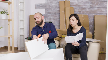 Couple assembling furniture using instructions in their new apartment