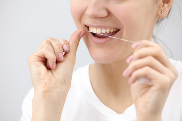 Oral hygiene and health care. Smiling women use dental floss of white healthy teeth on a white background. place for inscription