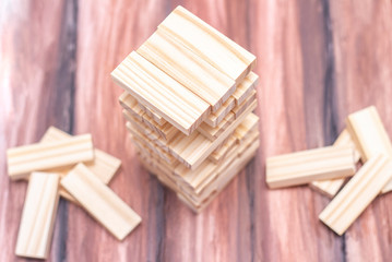 Close-up of a light wooden tower made of blocks. Board game Jenga on the table. Activity for strategy and concentration. Business concept