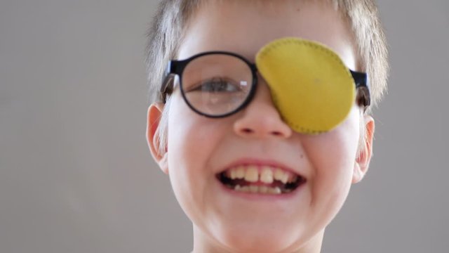 Portrait of funny child in new glasses with yellow spot to correct strabismus Orthopedic Boys Eye Patches nozzle for glasses for treatment of strabismus (lazy eye). Boy puts on and corrects glasses