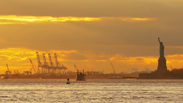 Beautiful sunset over New York Upper Bay and Statue of Liberty with ferry boat