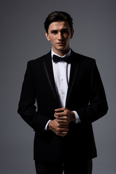 handsome young man in suit and tie bow, isolated on grey