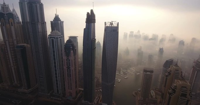 DUBAI, UAE - JANUARY 2, 2017: Aerial view of skyscrapers in Dubai Marina, at foggy sunrise. Dubai Marina is an artificial canal city, built along a two-mile (3 km) stretch of Persian Gulf shoreline.