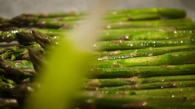 oiling fresh green asparagus stems with the brush before baking close up