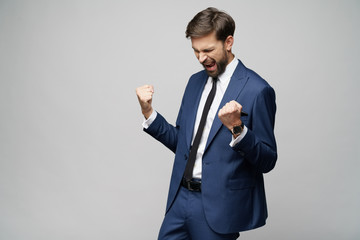 Very happy successful winner gesturing businessman over grey background