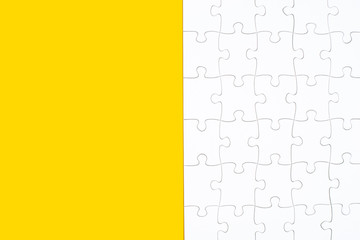 White jigsaw puzzle on yellow background with copy space