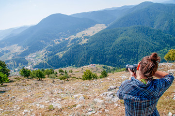 A young woman taking a photo on a mountain. Lifestyle blogging/vlogging about healthy living, nature and outdoors.