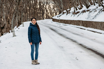 young woman walks on a winter road in forest