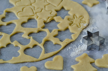 Raw cookies being cut with a star and heart cookie cutter