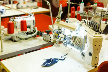 Modern sewing machine, blue fabric, sewing accessories, red thread bobine