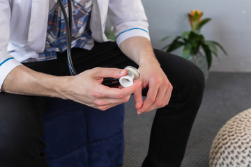 Doctor holding stethoscope in his hand wearing medical gown, ready to examine a patient. Close Up