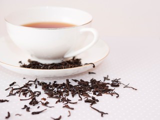 black loose tea sprinkled next to a cup of tea