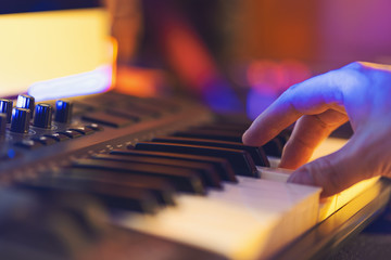 Music studio. Produce electronic music and play on midi keyboard. Close-up shallow depth of field view on hand