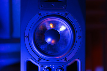 Music loudspeaker sound system in neon blue light. Dynamic monitor in studio close-up