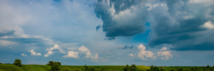 Obraz na płótnie Canvas Clouds over field in hilly terrain.