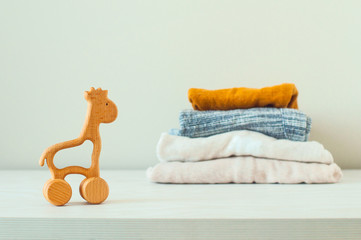 Wooden toy giraffe near baby clothes on the shelf