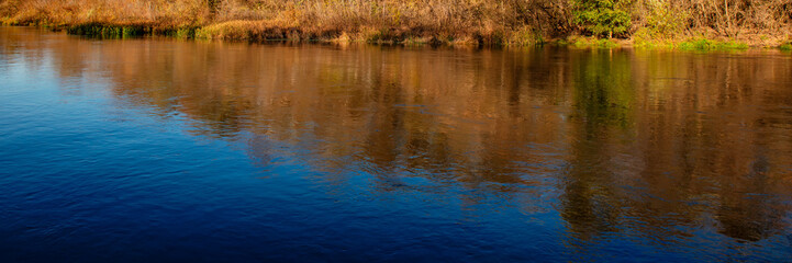 Reflection on the surface of water in the river. Natural landscape. Autumn season.
