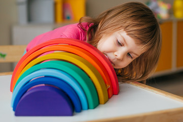 Beautiful little girl playing with wooden rainbow