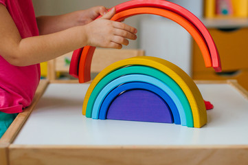 Closeup of little girl playing with colorful wooden toy rainbow