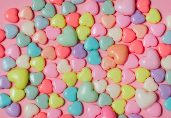 Background of colorful heart shape beads on pink background
