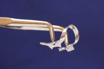 Dentist's hand with dental tongs and clasp.