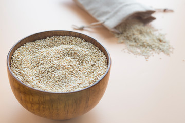 Uncooked Quinoa in wooden bowl with textil bag